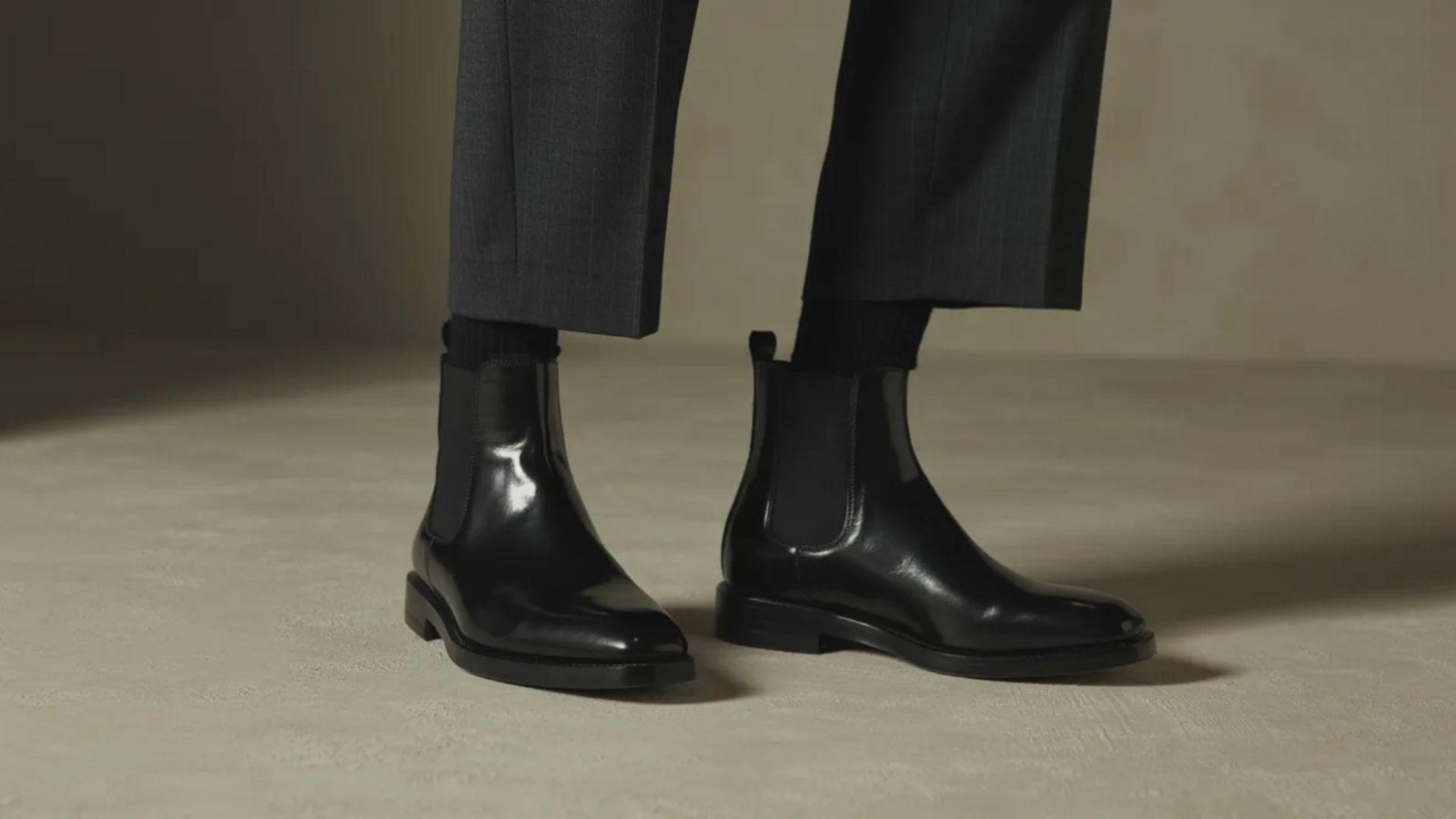 A well-dressed individual in a suit and black boots exudes professionalism and style.