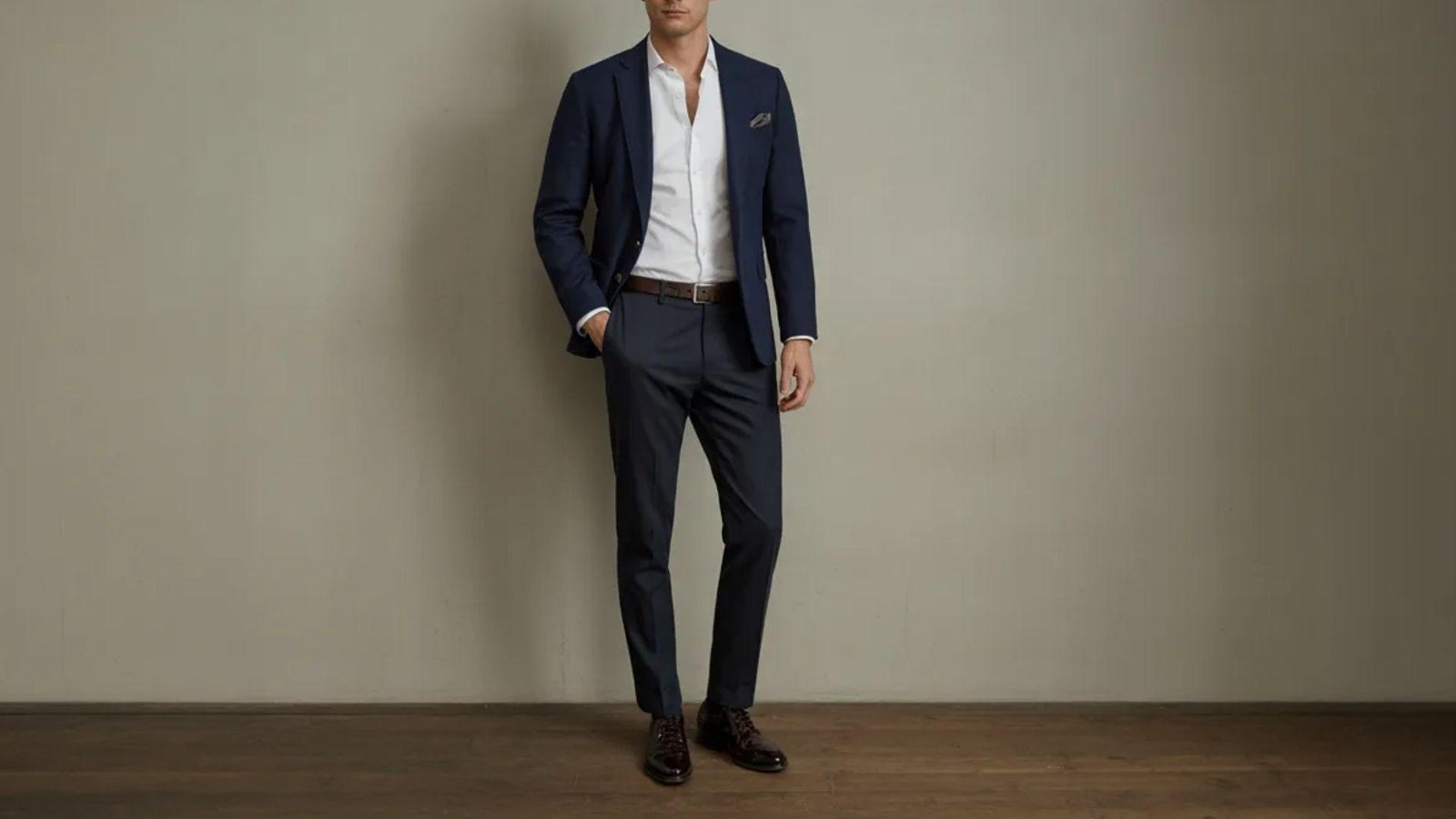  A man wearing a blue suit and a white shirt stands confidently, showcasing a professional appearance.
