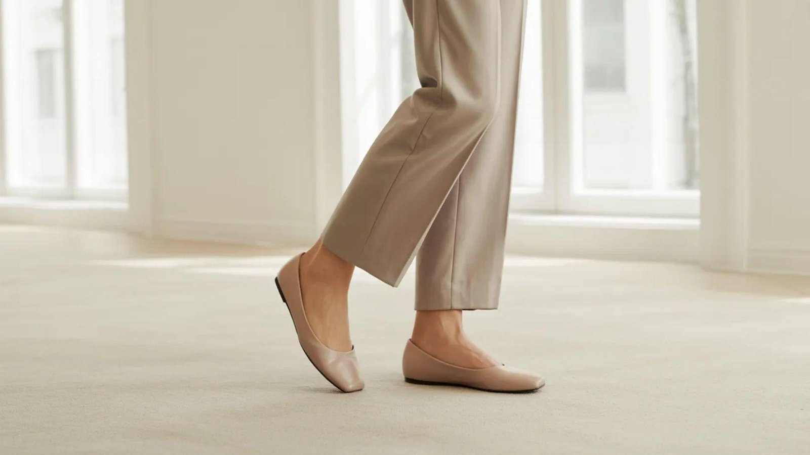 A woman dressed in pants and shoes stands confidently, showcasing her casual yet stylish outfit.