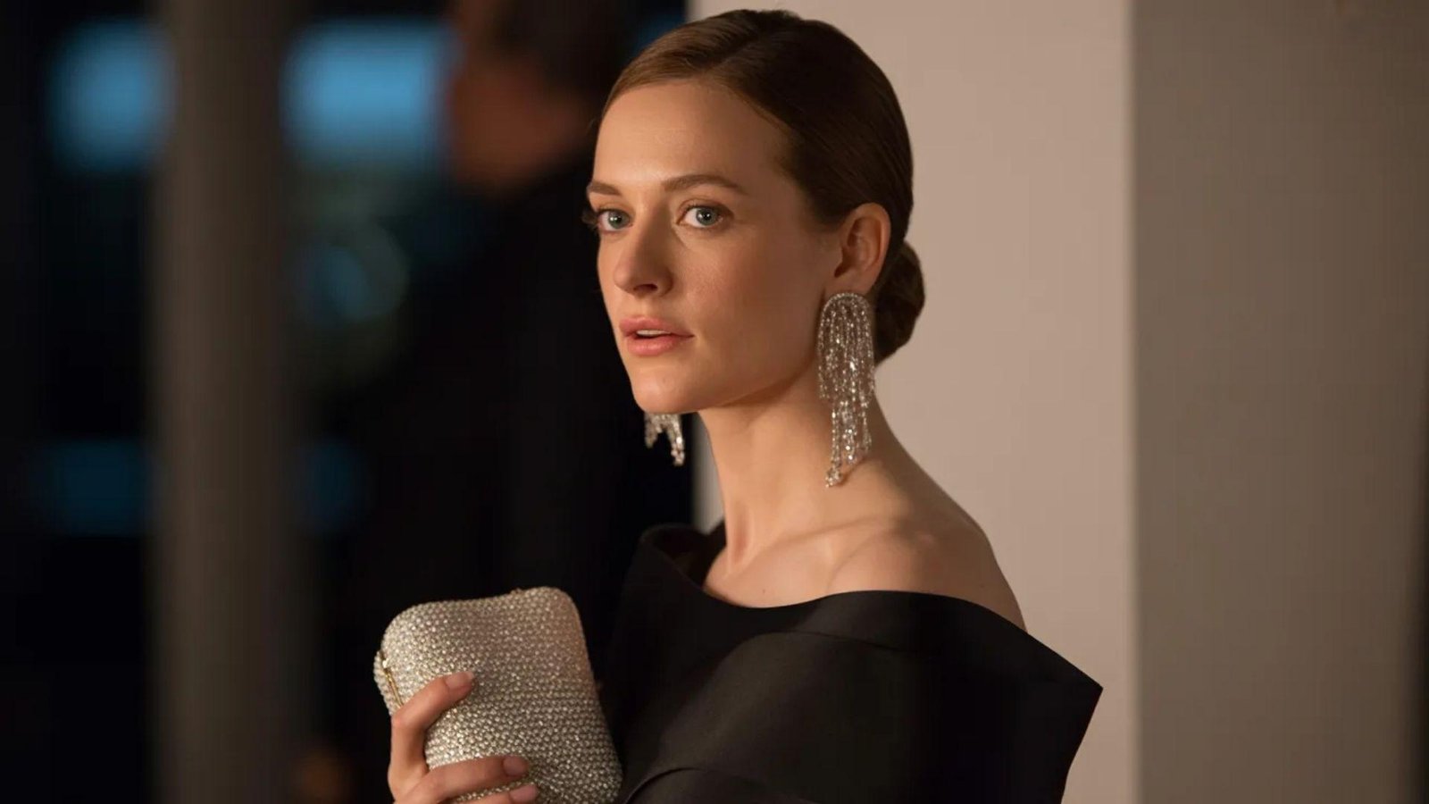 A woman in a black dress elegantly holds a clutch, showcasing a stylish and sophisticated look.