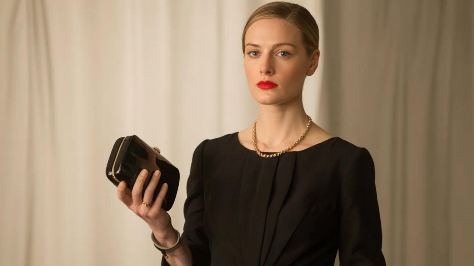 A woman in a sleek black dress carries a purse, exuding elegance and fashion-forward style.