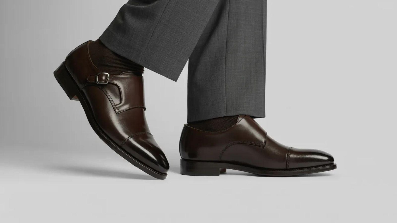 A man in a suit stands confidently, wearing brown shoes that complement his formal attire.