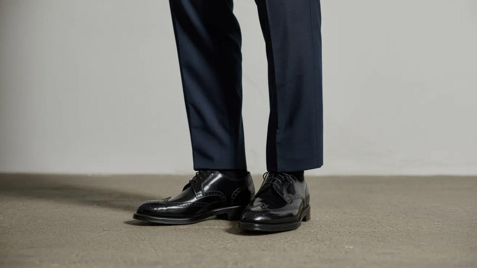 A well-dressed individual in a suit and black shoes exudes professionalism and style.