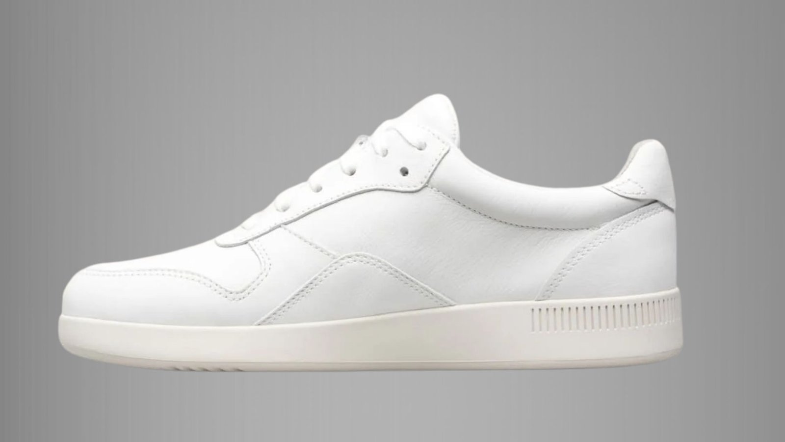 A white leather sneaker featuring a matching white sole, showcasing a sleek and minimalist design.