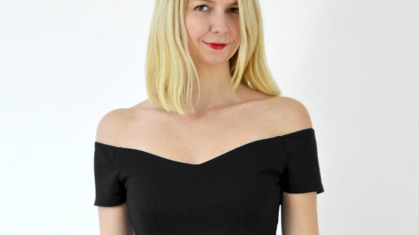A woman wearing a black off-the-shoulder top, showcasing her shoulders and a stylish, elegant look.