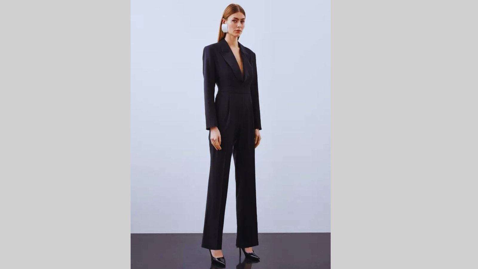 A woman wearing a tailored black blazer and jumpsuit, complemented by stylish heels.
