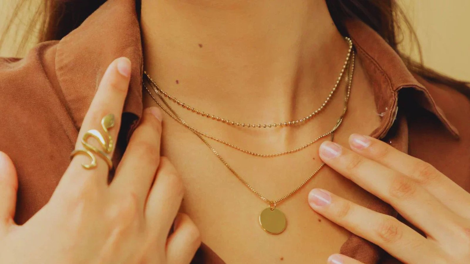 A woman models a necklace featuring three distinct rings, showcasing a blend of styles and materials.
