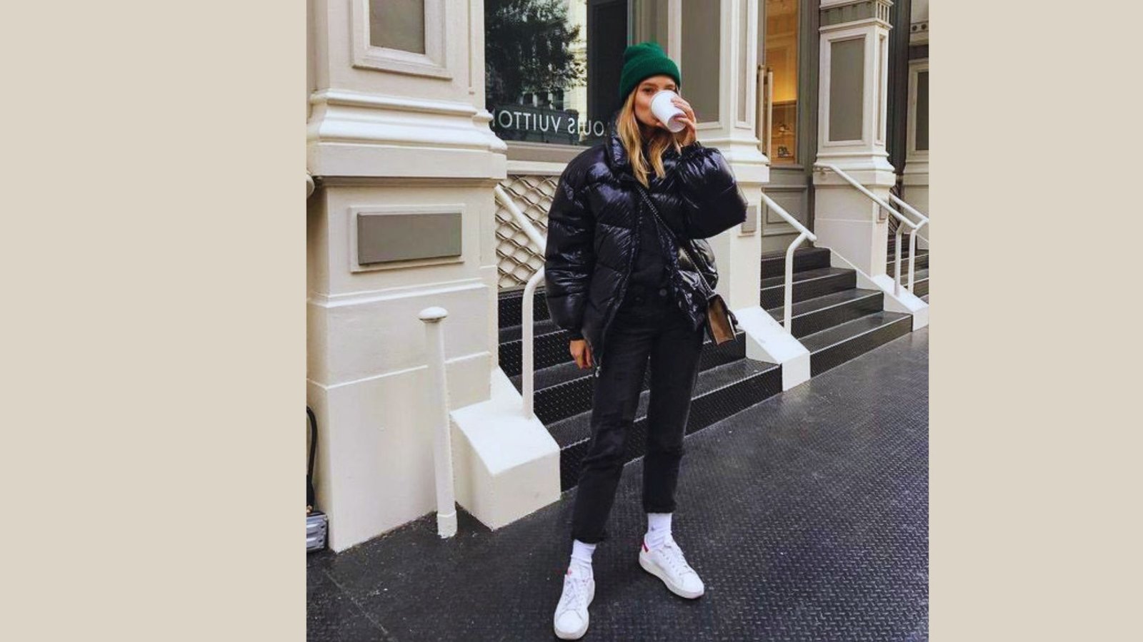A woman wearing a black cropped puffer jacket and white sneakers, showcasing winter fashion style.
