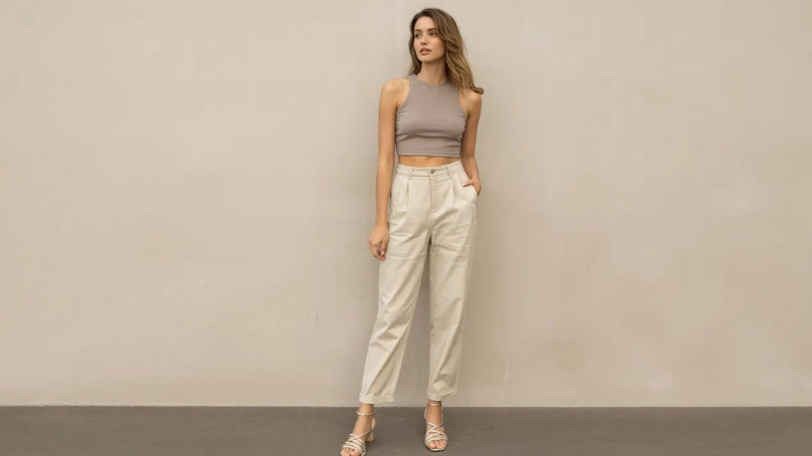 A model showcases a stylish outfit featuring a cropped top paired with high-waisted pants.
