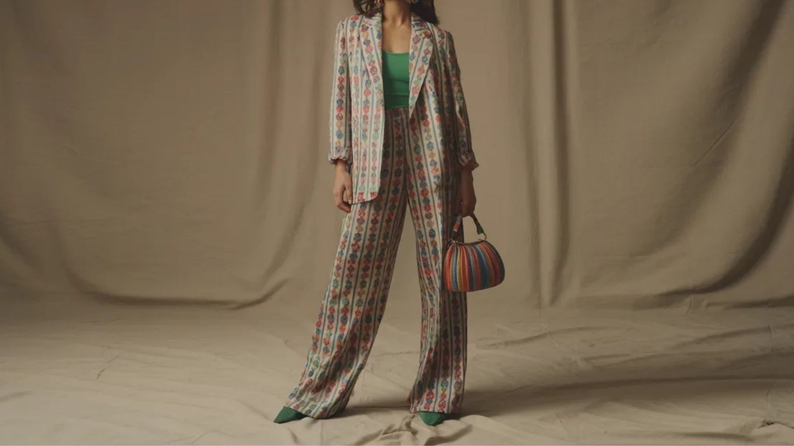 A model wearing a plaid suit holds a green bag, showcasing a stylish and contemporary fashion look.
