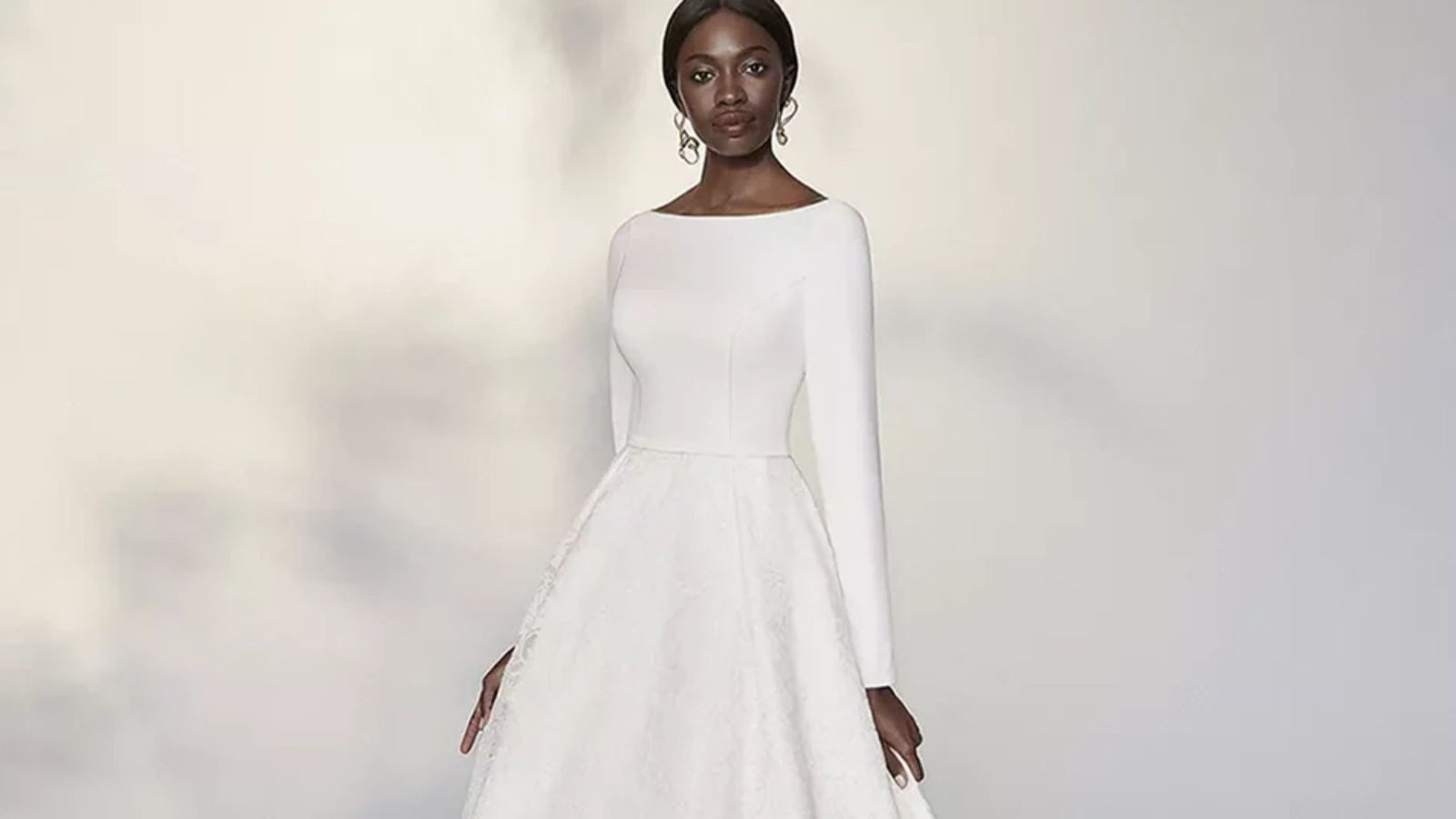 A white wedding dress featuring long sleeves and a flowing long skirt, elegantly designed for a classic bridal look.