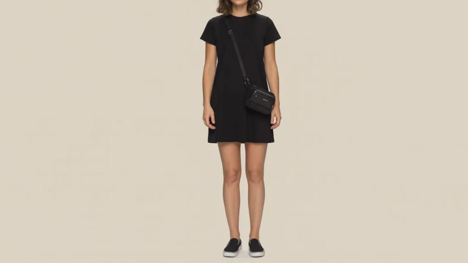 A model displays a fashionable black dress complemented by sporty sneakers.