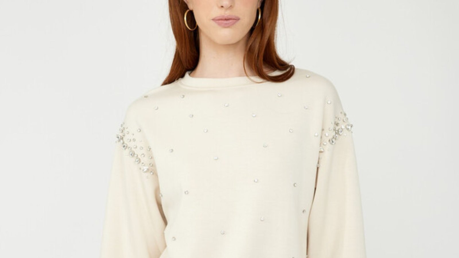 Soft cream-colored knit sweater displayed on a neutral background, showcasing its texture and cozy appearance.