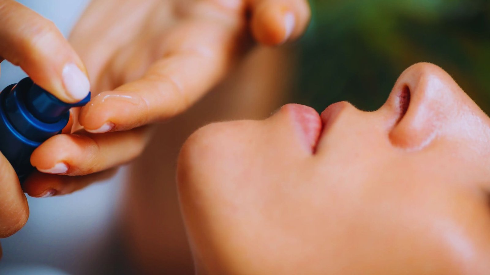A woman receives a facial treatment using a blue device, focusing on her face in a serene setting.