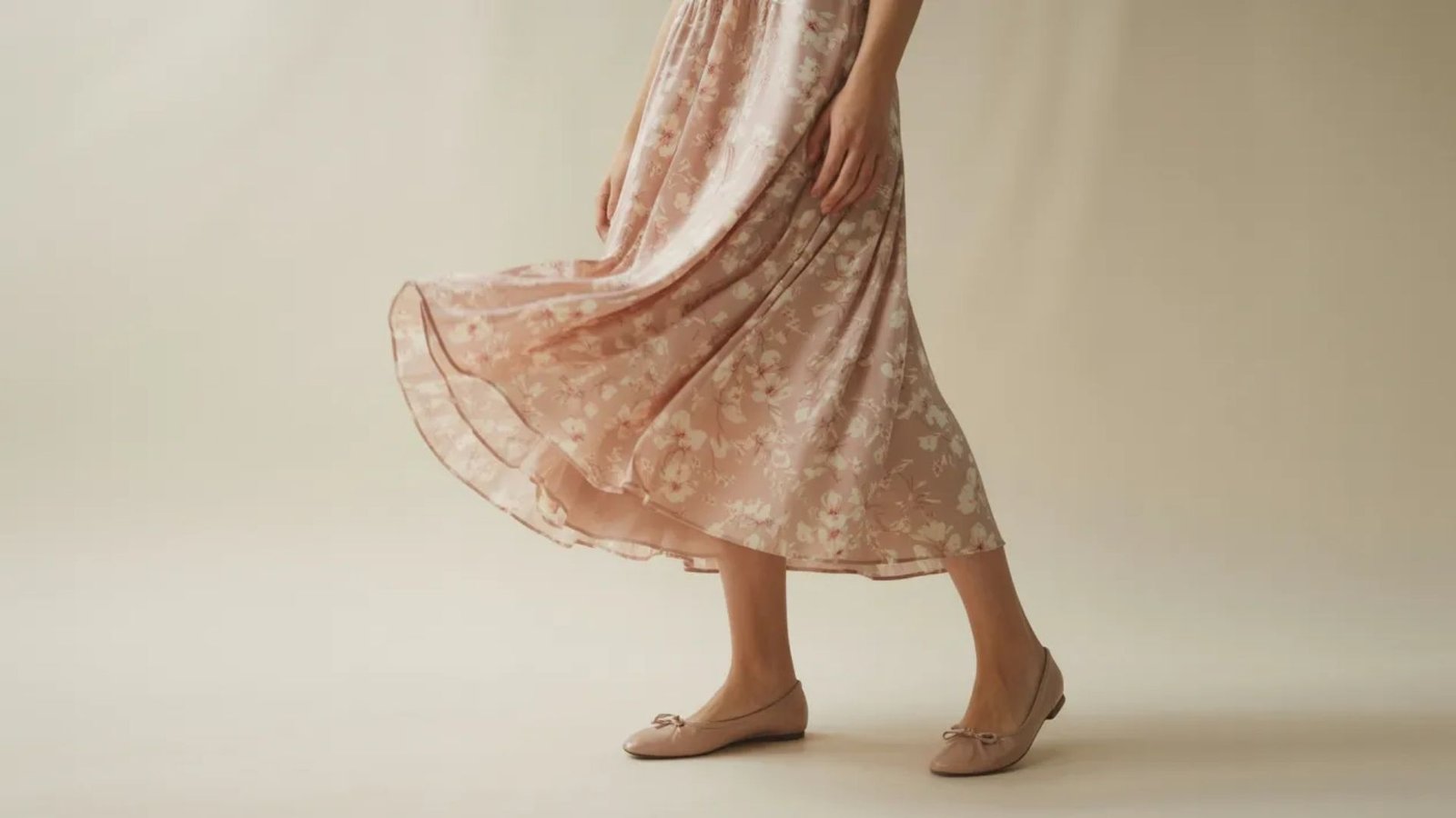 A model poses in a pink dress adorned with a vibrant floral print, showcasing a stylish and feminine look.
