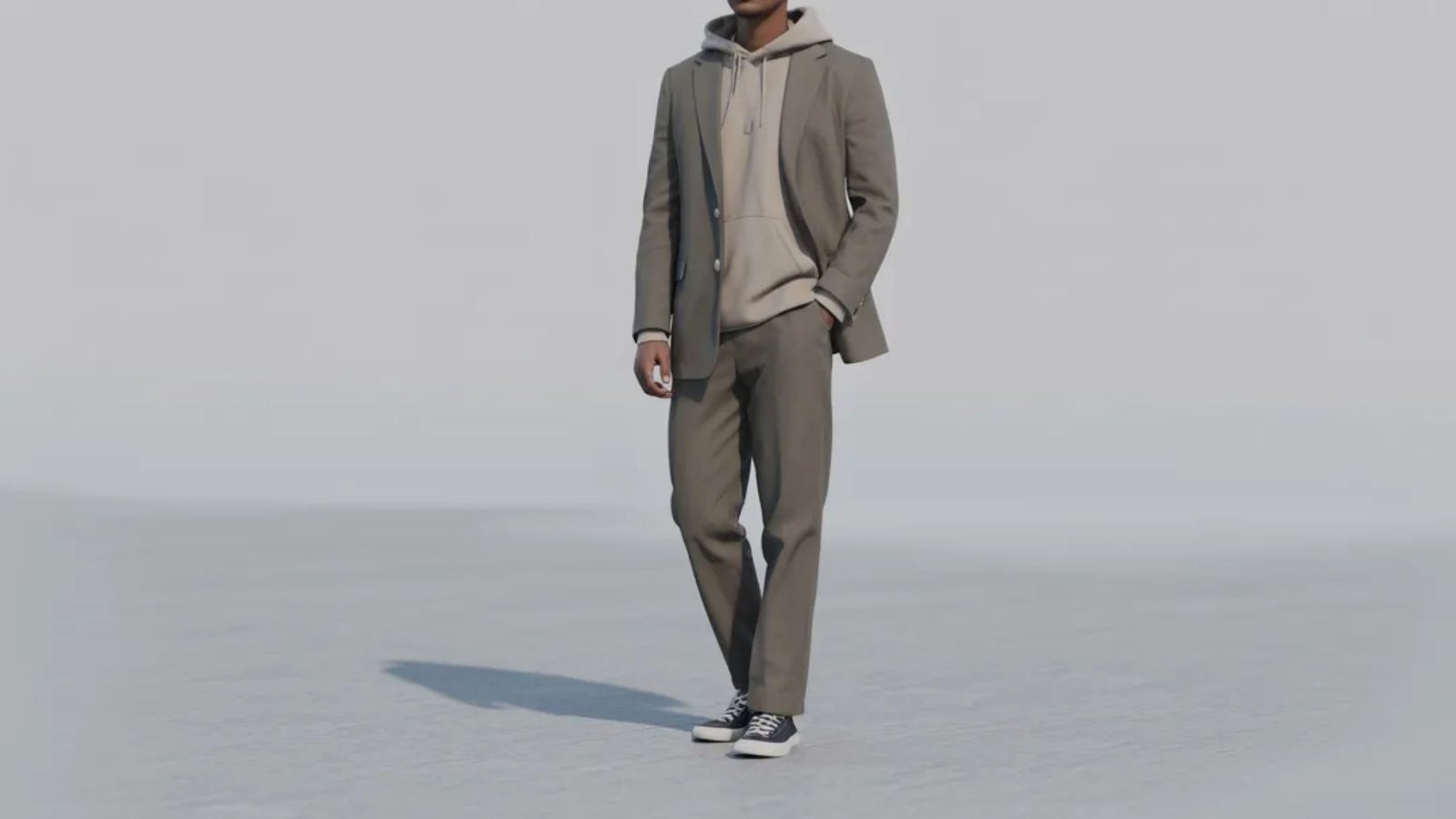 A man wearing a suit and sneakers stands on a snowy field, showcasing an unusual mix of formal and casual fashion.