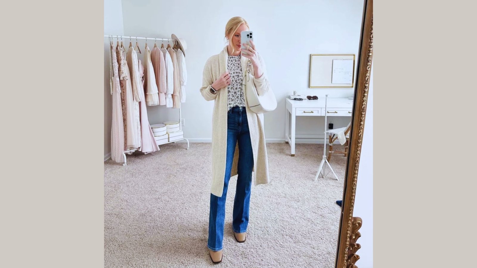 A woman smiling while taking a selfie in front of a mirror, capturing her reflection and the surrounding room.