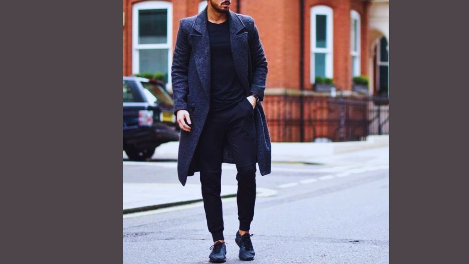 A man dressed in black clothing and a long coat stands confidently, exuding a mysterious aura.