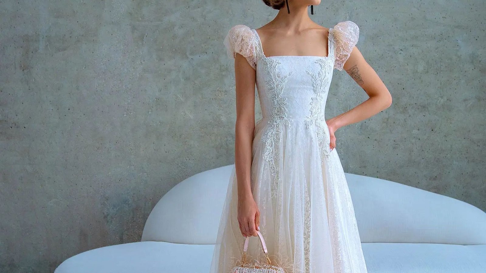A woman in a wedding dress poses elegantly for the camera, showcasing her joyful expression and beautiful attire.