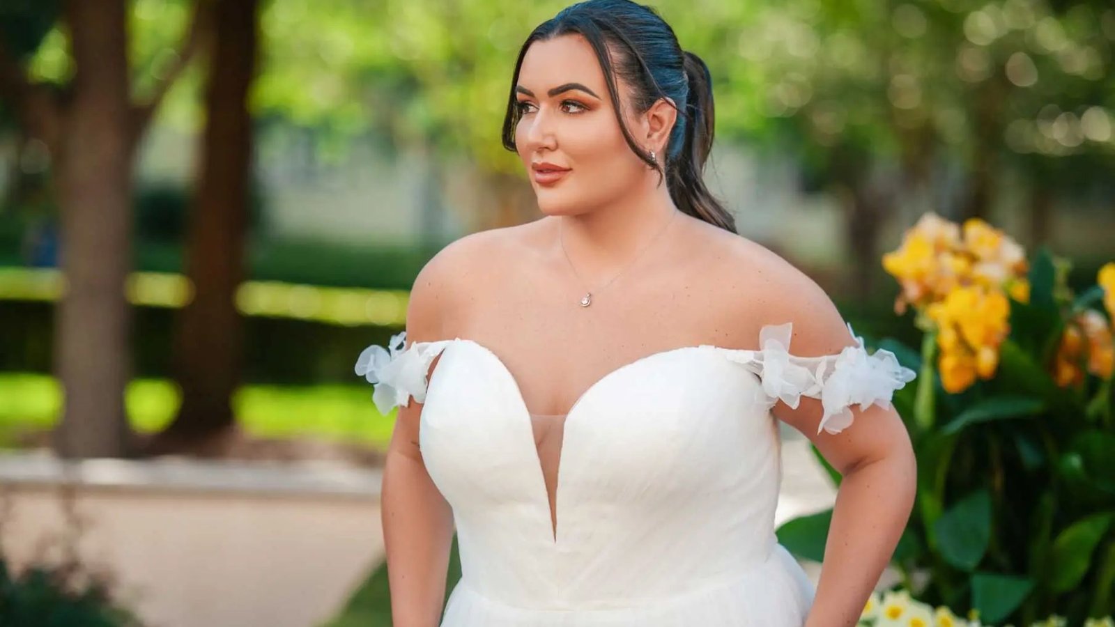 A woman in a beautiful wedding dress poses gracefully for a photo, showcasing her joyful expression and elegant attire.
