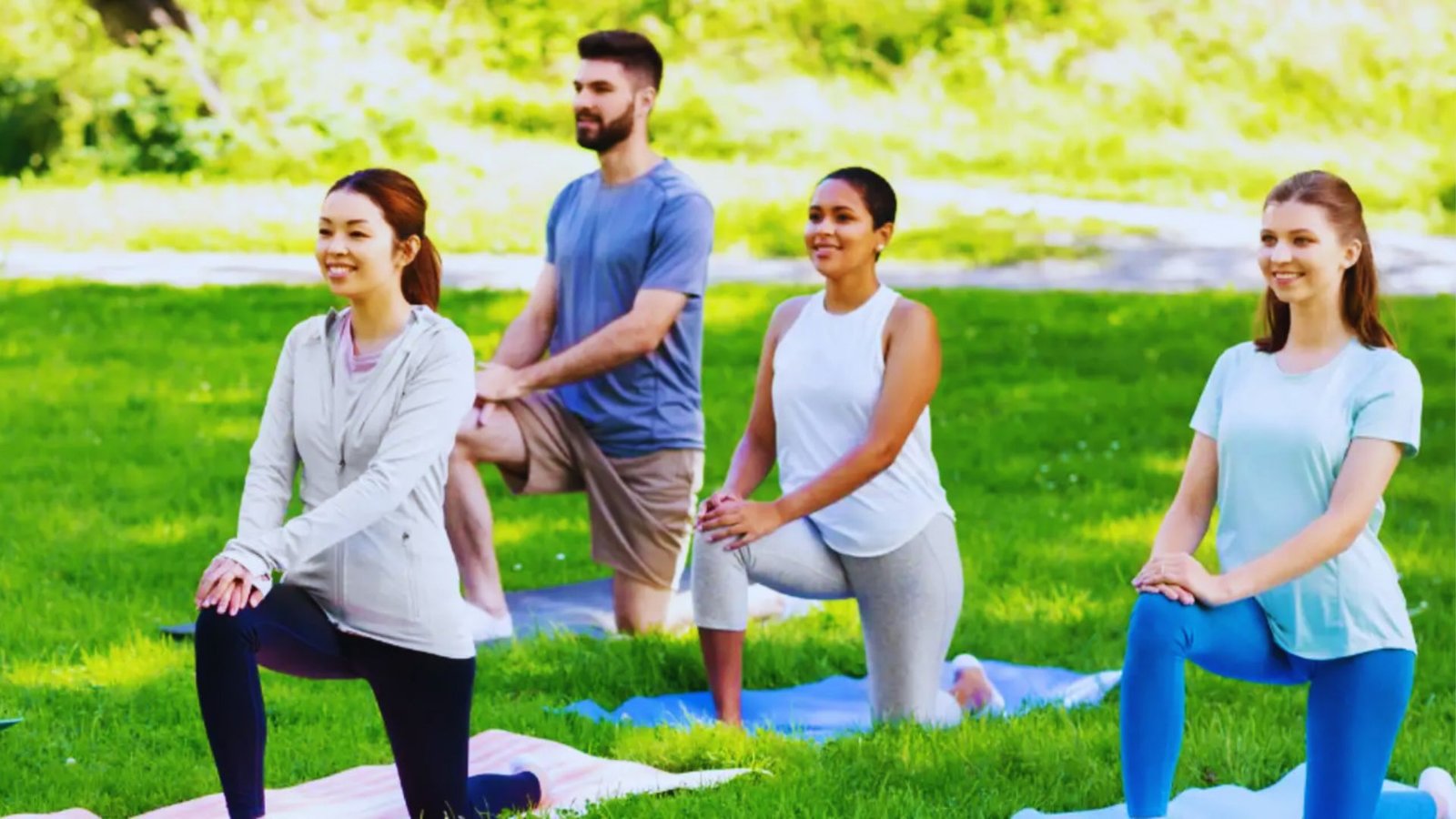 A group of people practicing yoga in a sunny park during summer, showcasing a casual outdoor fitness session.
