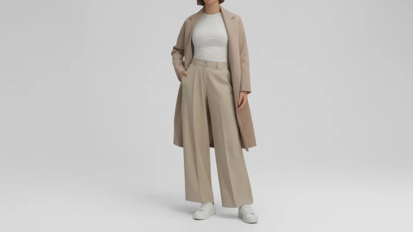 A model wears a fashionable beige coat and wide pants, presenting a sophisticated and trendy outfit choice.
