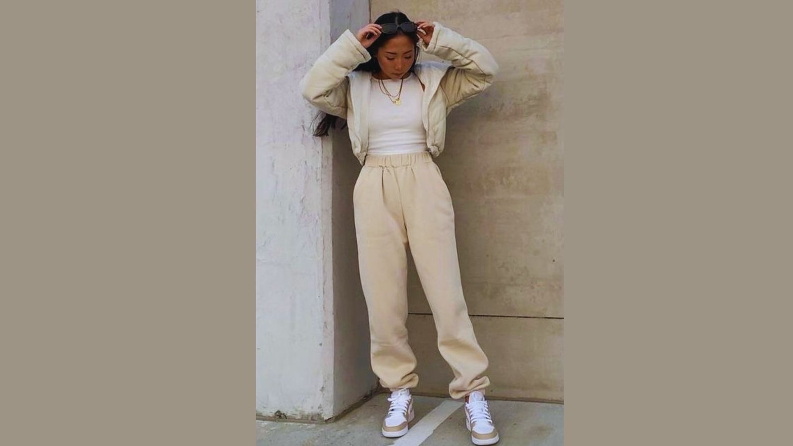 A woman in a white top and beige pants stands confidently, showcasing a casual yet stylish outfit.