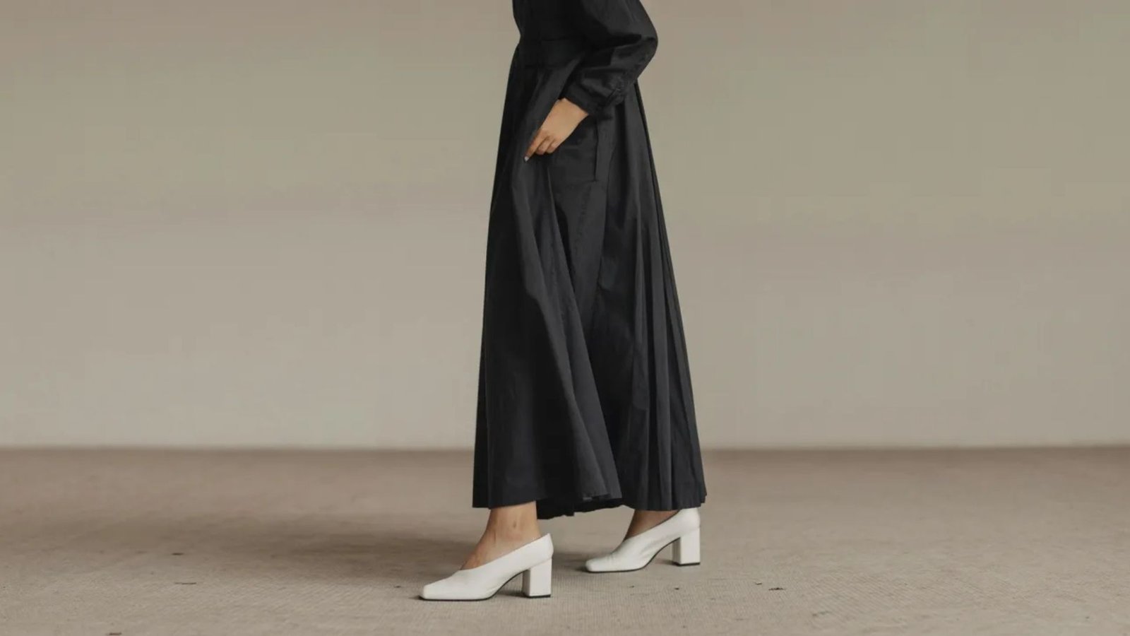 A model showcases a black long-sleeve dress with a high neck, emphasizing elegance and sophistication.