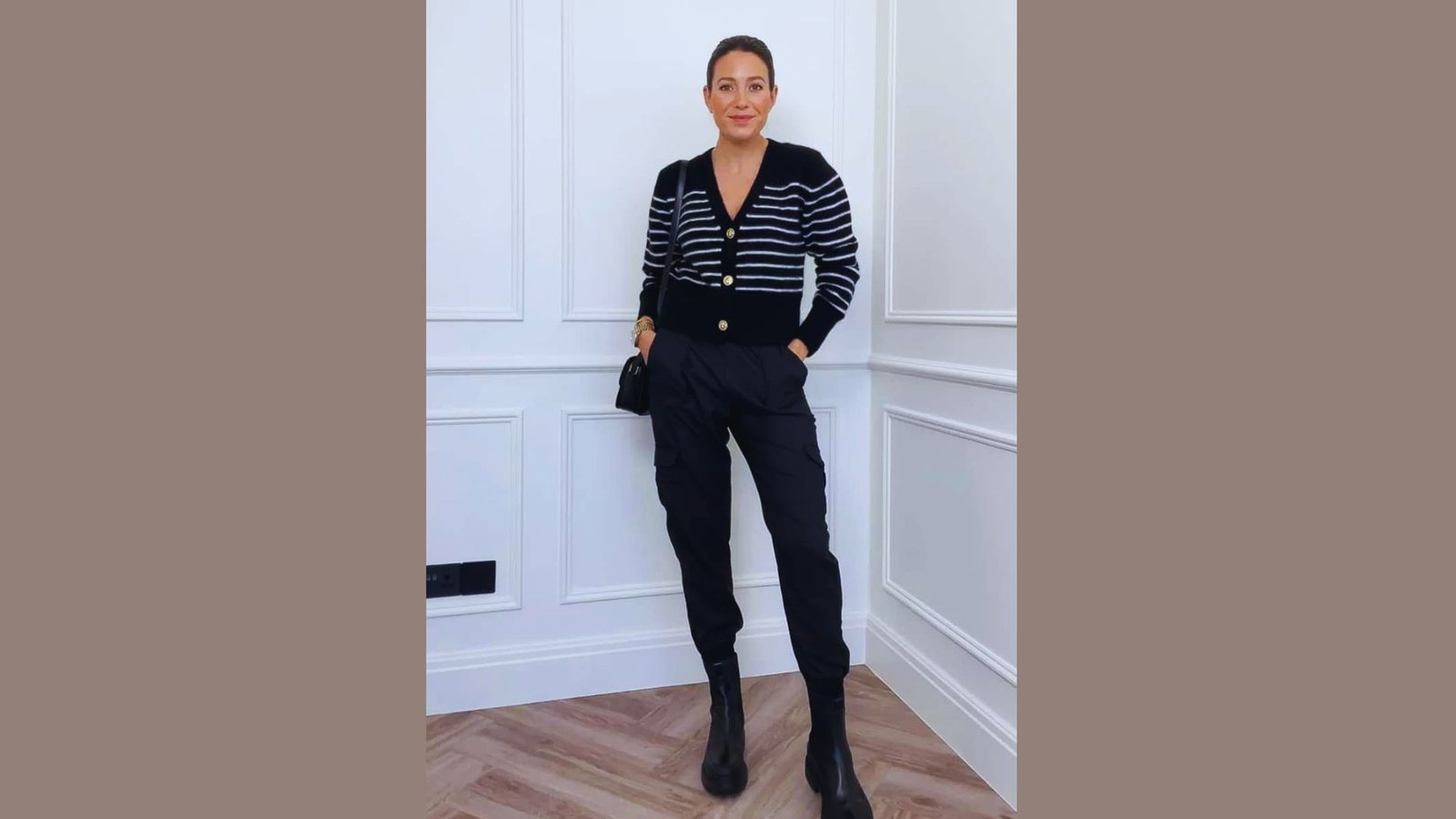 A woman wearing a black and white striped sweater and matching pants stands confidently, showcasing her stylish outfit.