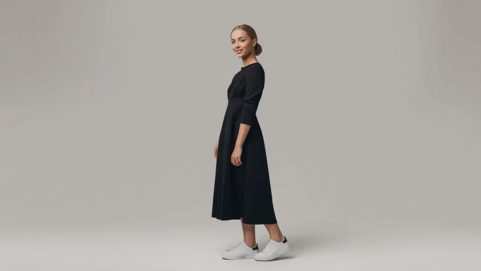 A woman dressed in a black dress and white sneakers exudes a modern and chic vibe, perfect for casual outings.
