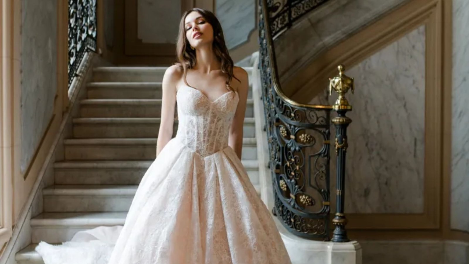 A woman in a wedding dress stands gracefully on a staircase, radiating elegance and joy.