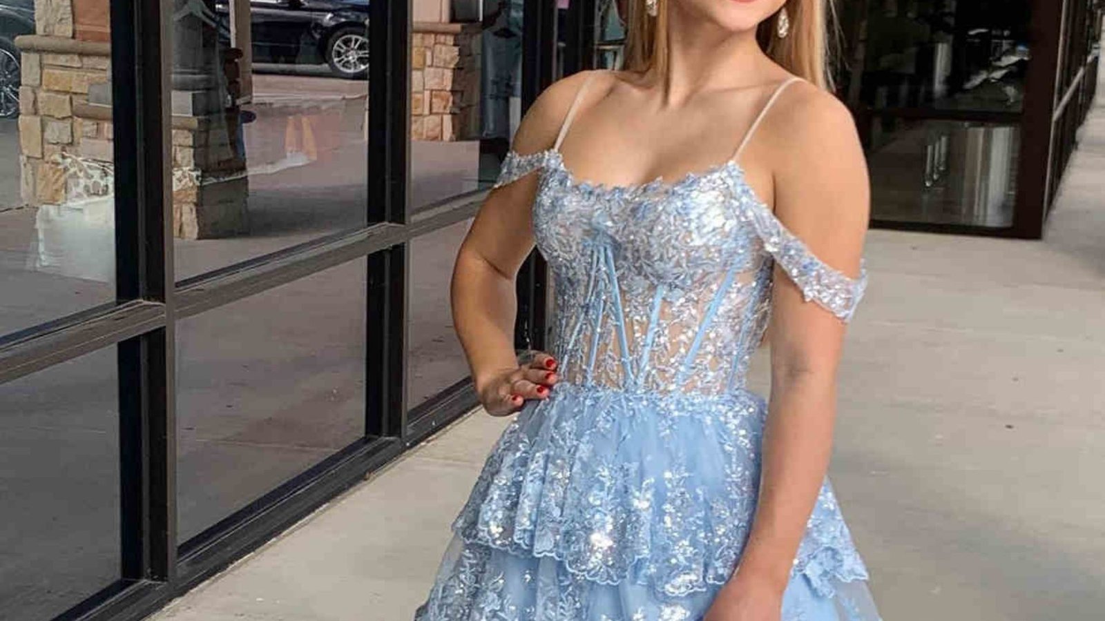 A beautiful young woman wearing a blue dress, smiling softly against a neutral background.