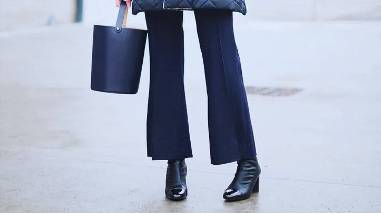 A woman in a puffer jacket and wide-leg pants stands confidently, showcasing a stylish winter outfit.