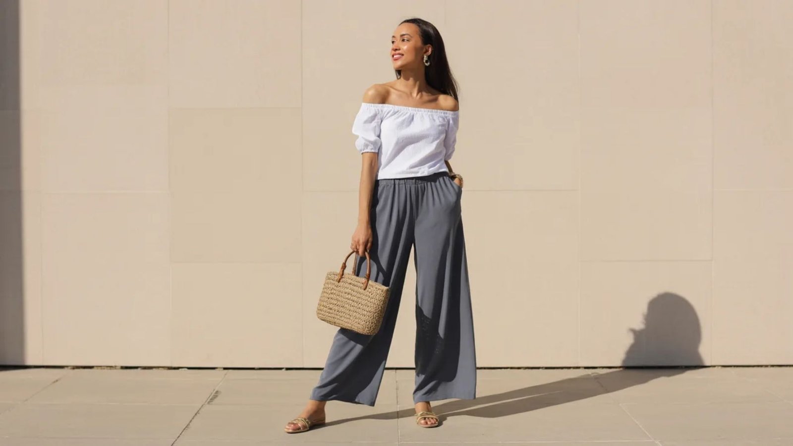 A woman models wide leg pants and a white top, embodying a chic and contemporary fashion style.