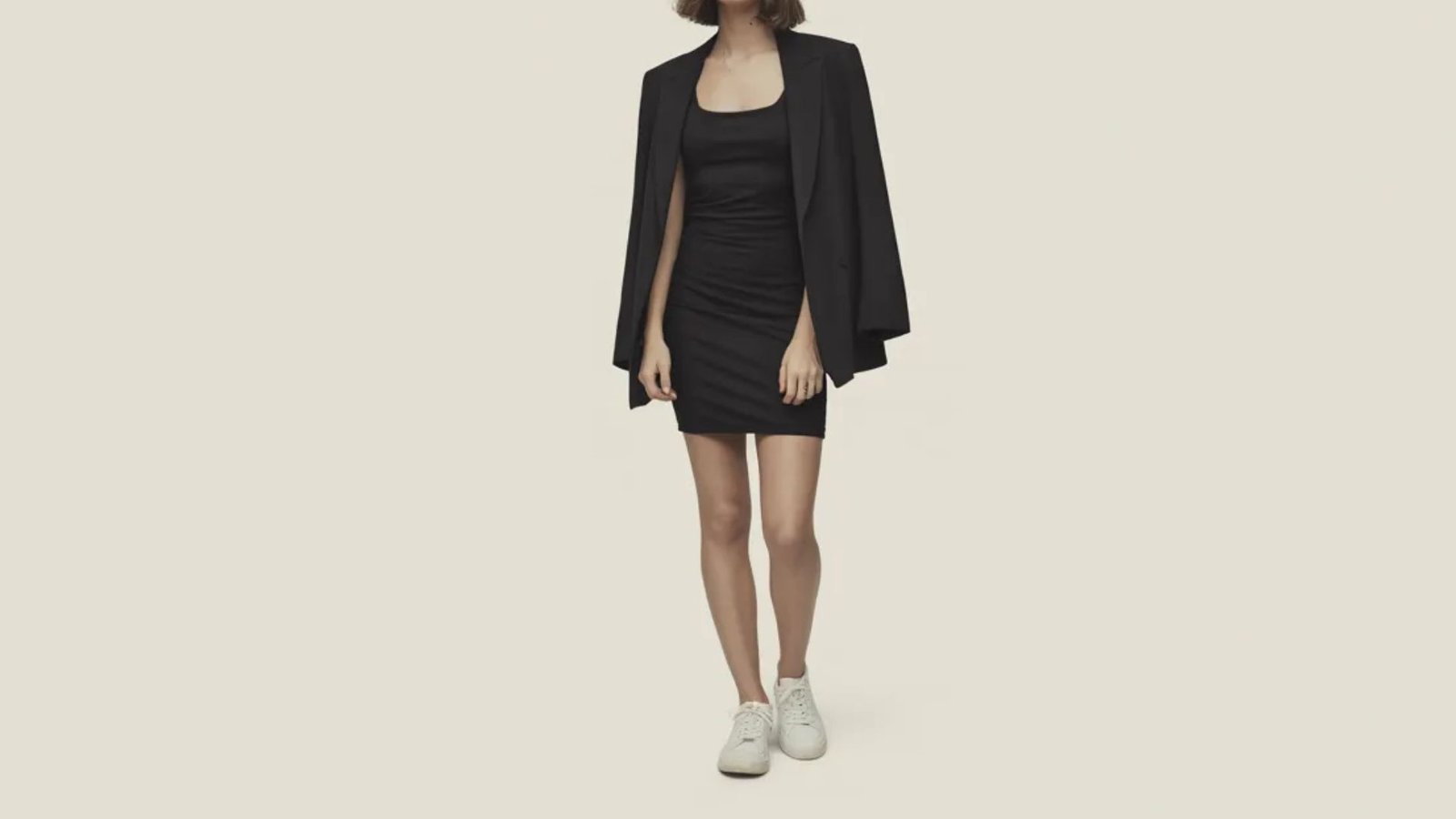 A woman dressed in a black dress and jacket poses gracefully, exuding sophistication and poise.