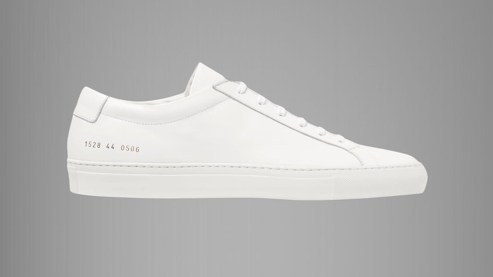 A white leather sneaker featuring a sleek design and a matching white sole.