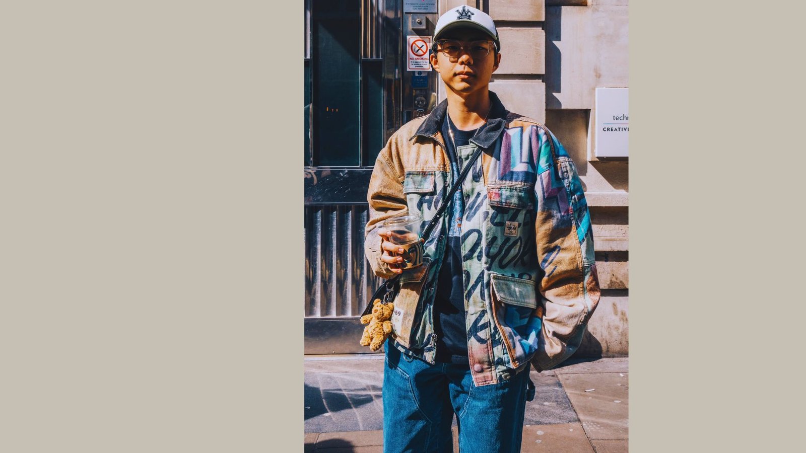  A man dressed in a jacket and jeans stands on the street, showcasing the shift towards tailored streetwear.

