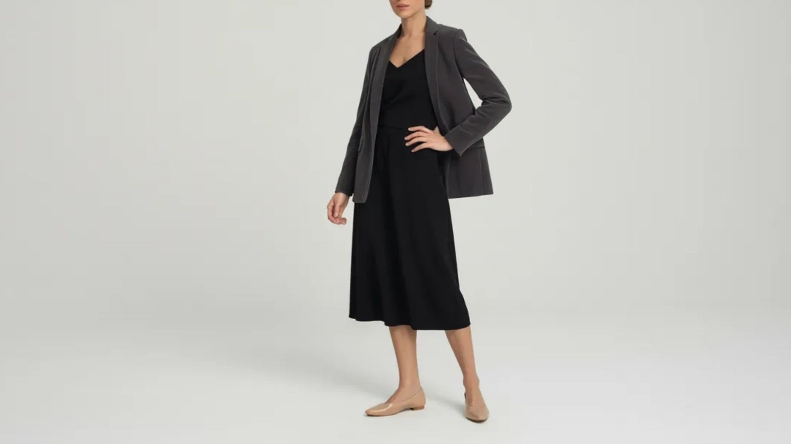 A model showcases a stylish black dress paired with a matching jacket, exuding elegance and sophistication.