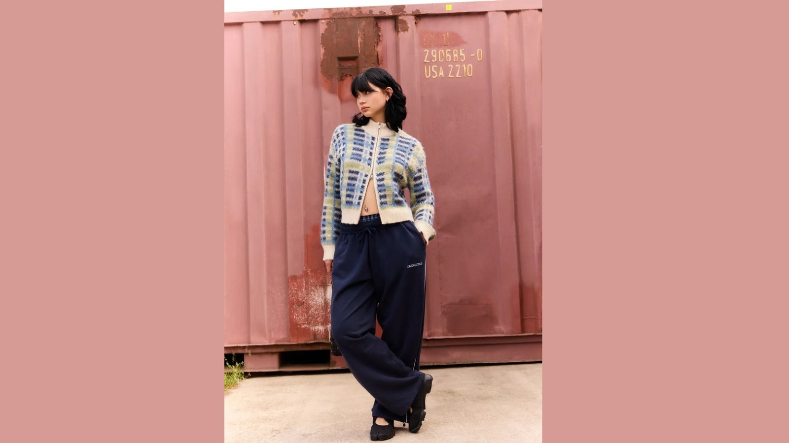 A woman wearing a blue and white sweater with matching pants stands confidently, showcasing her stylish outfit.