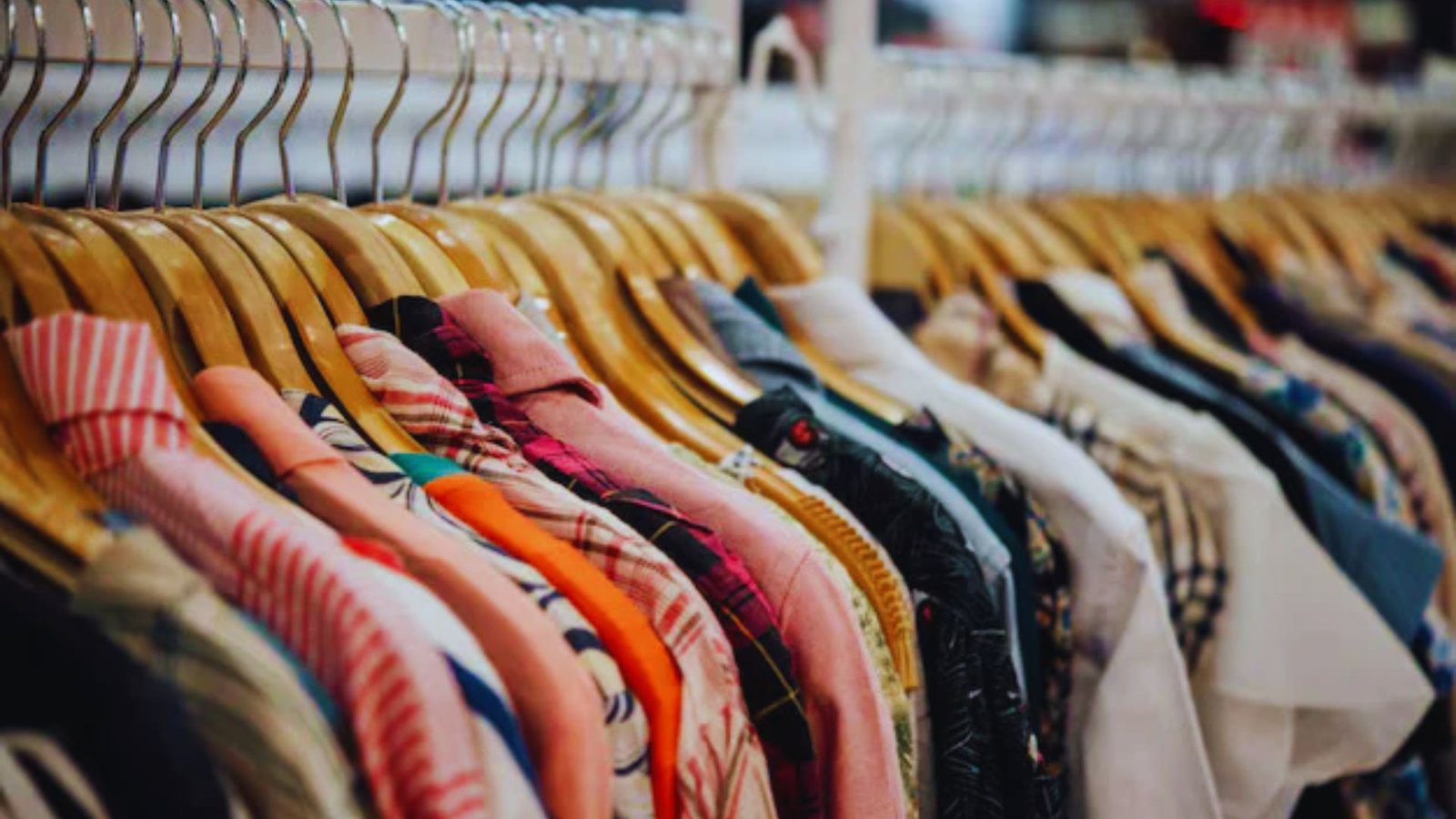 A variety of clothing items displayed on hangers, showcasing different styles and colors in a retail setting.
