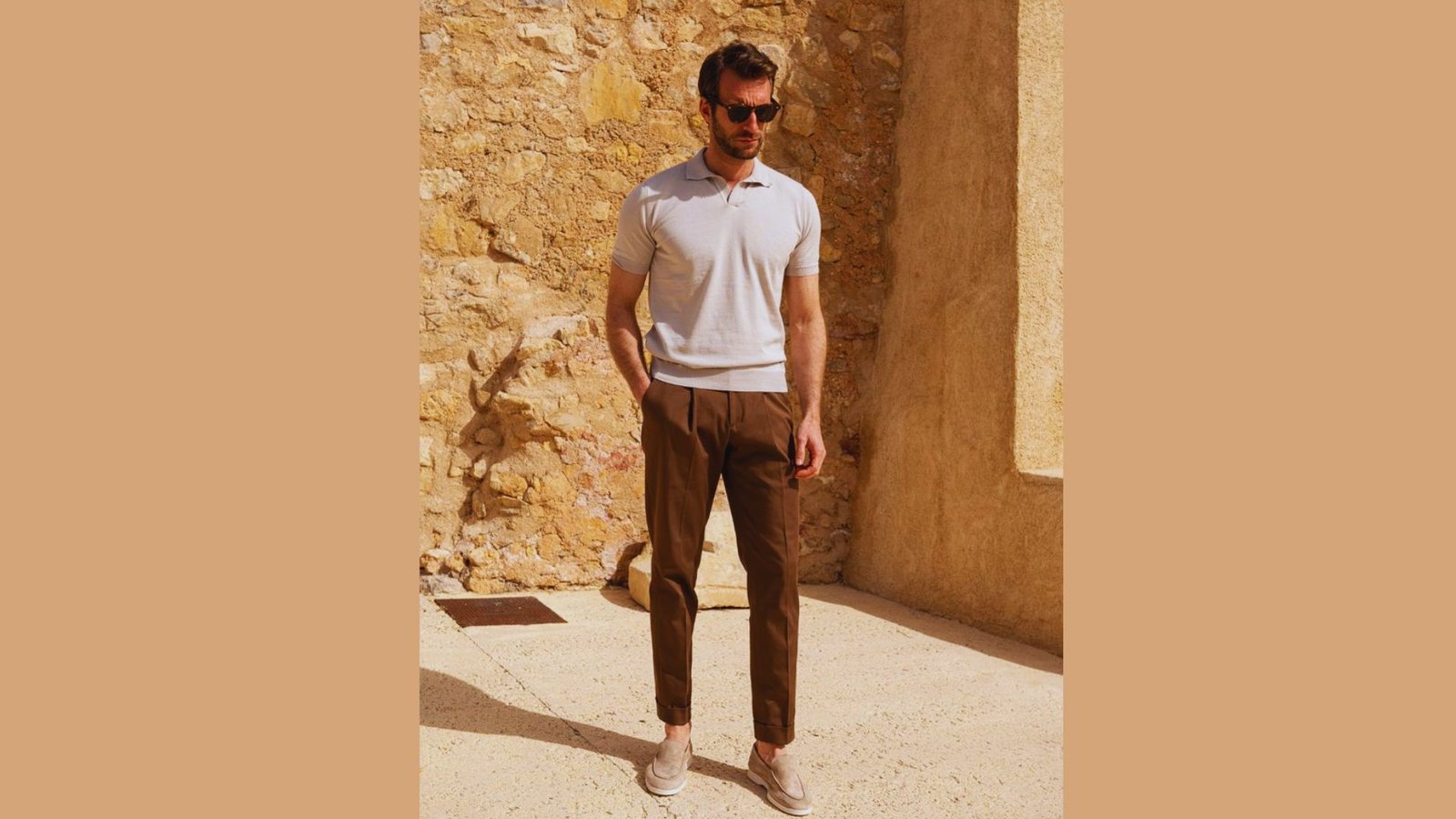 A man dressed in a polo shirt and brown pants poses, exemplifying a relaxed and stylish outfit.