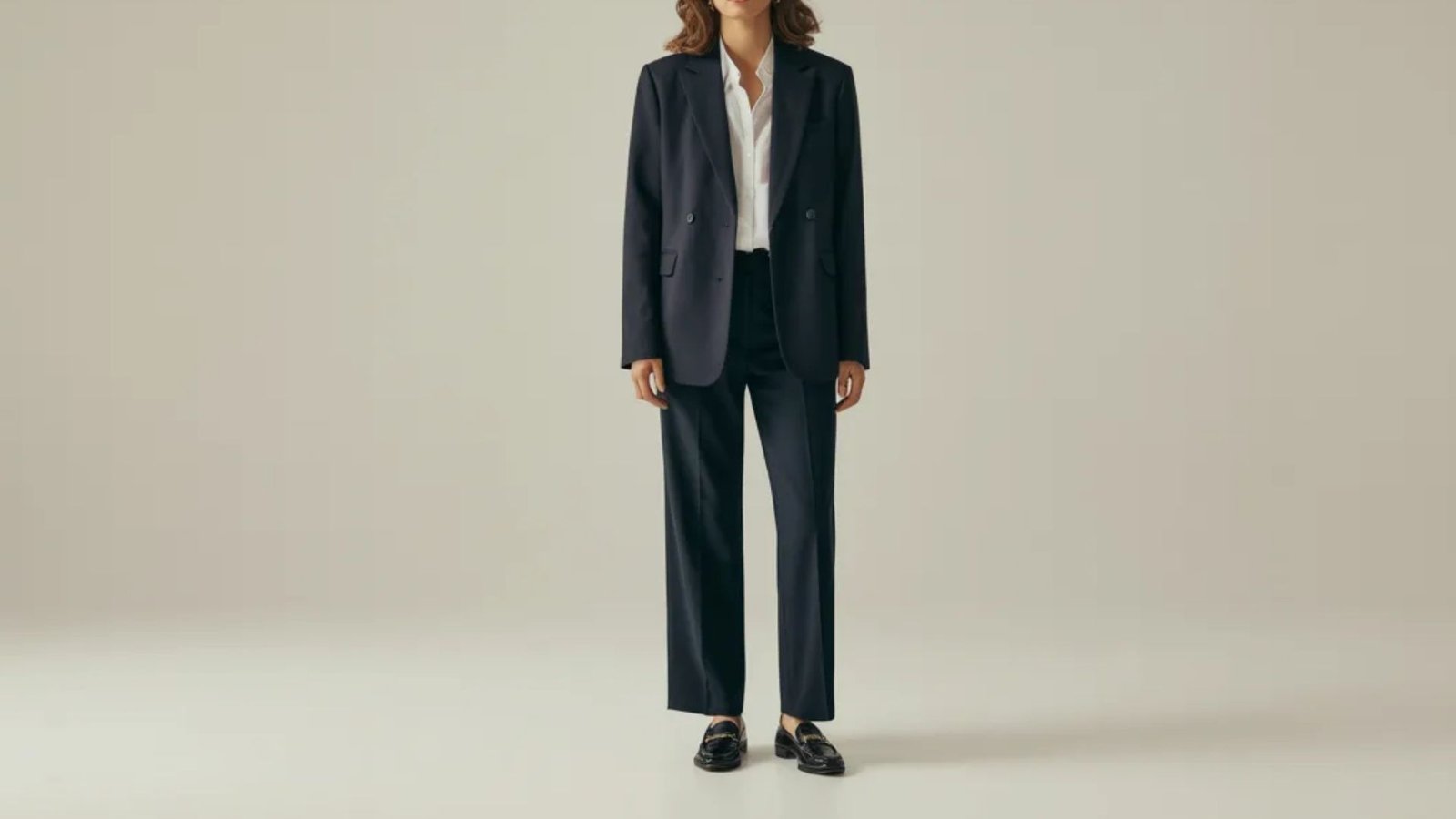 A model in a tailored navy suit and white shirt presents a sophisticated and polished look.