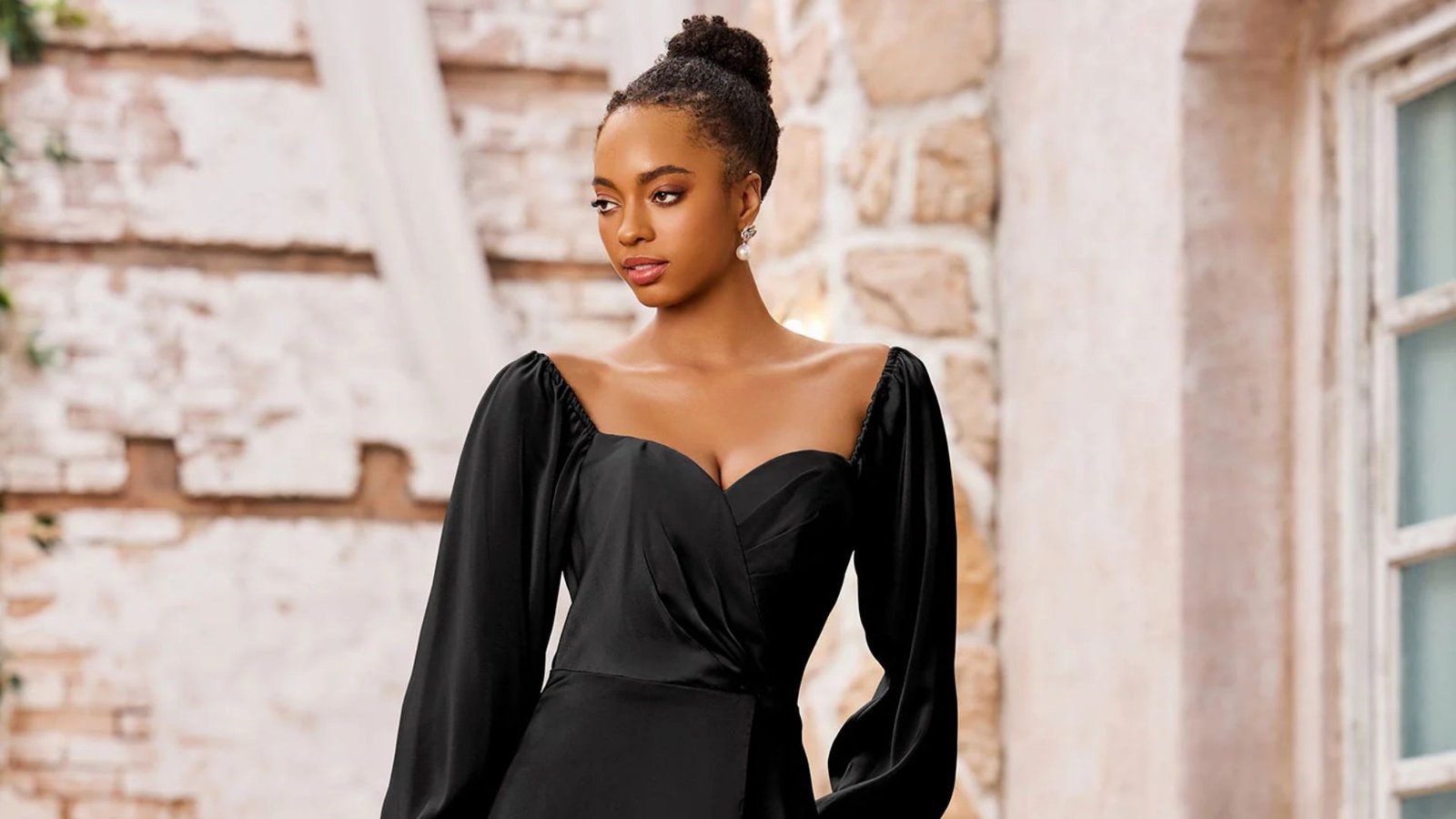 A woman in a black dress poses confidently for the camera, showcasing her elegant style and poise.