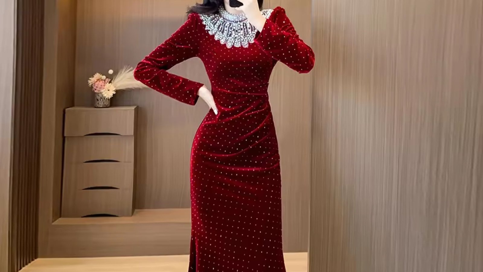 A woman in a red velvet dress smiles as she takes a selfie, capturing her stylish look and joyful expression.