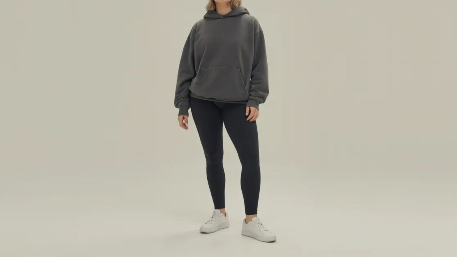 A model poses in a grey hoodie and leggings, showcasing a casual and comfortable outfit.
