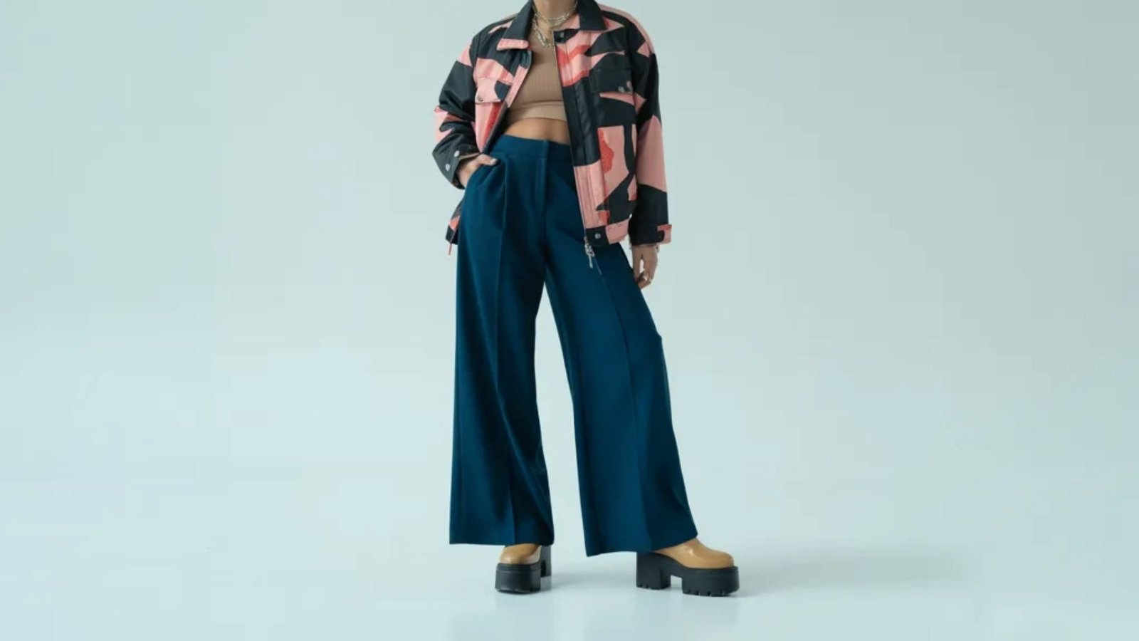 A model is dressed in a pink and black jacket along with wide-leg pants, highlighting a fashionable look.
