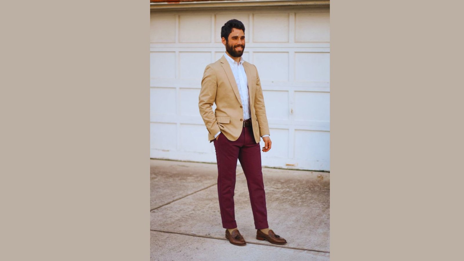 A man wearing a suit with maroon pants, standing confidently with a neutral expression.