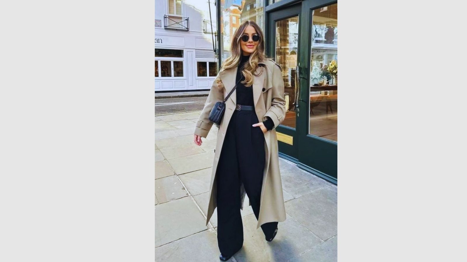 A woman wearing a long trench coat and black pants, suitable for formal events.
