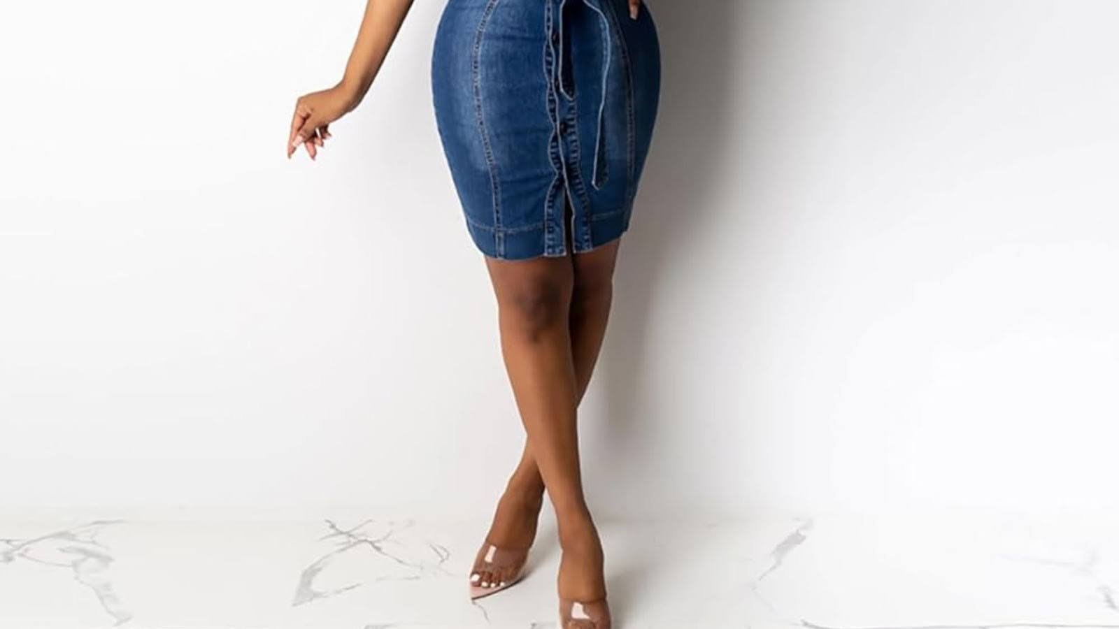 A woman wearing a denim skirt and matching top stands confidently, showcasing a casual yet stylish outfit.