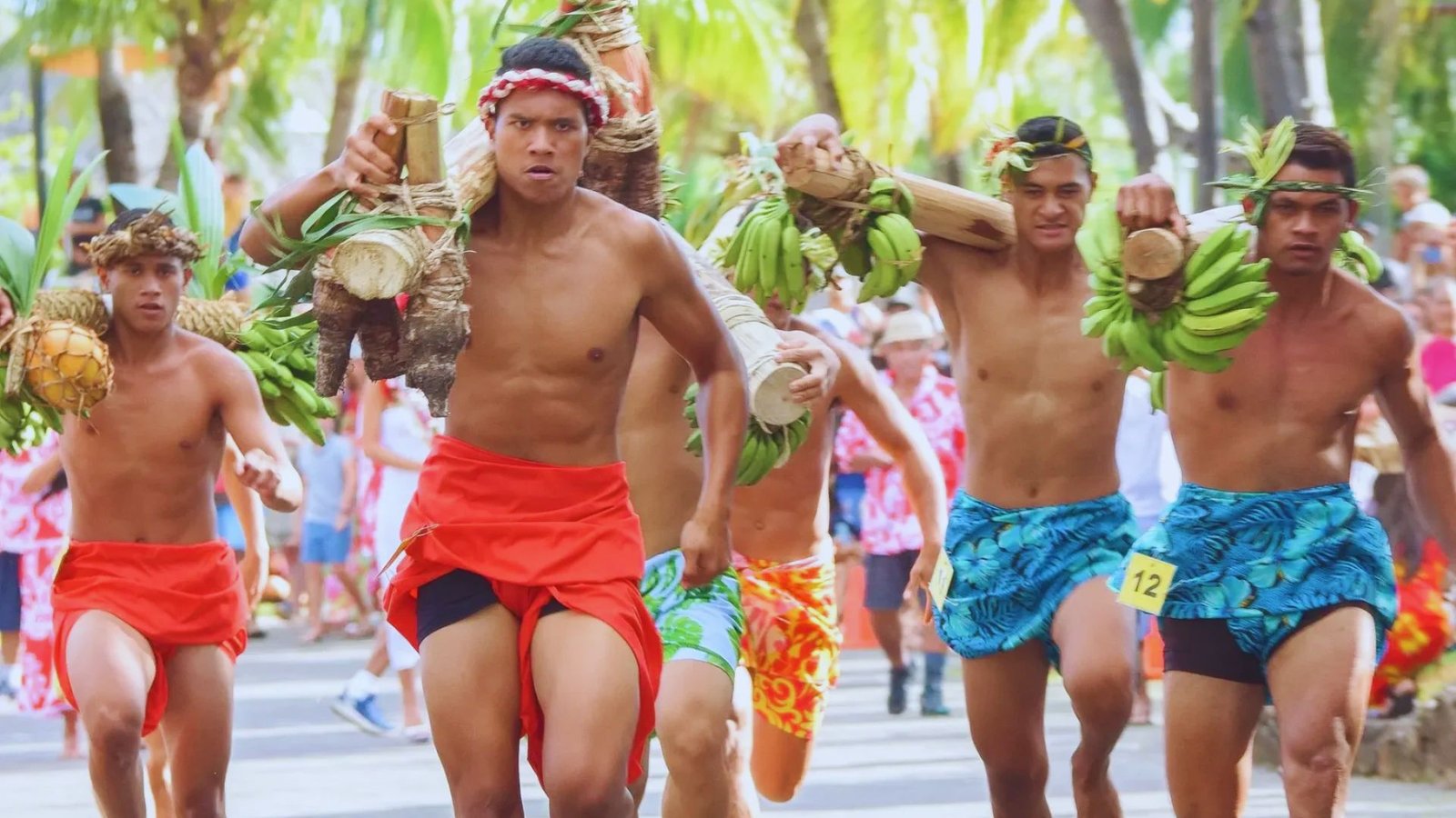 A group of men running in a parade, each holding a banana, with festive decorations in the background.